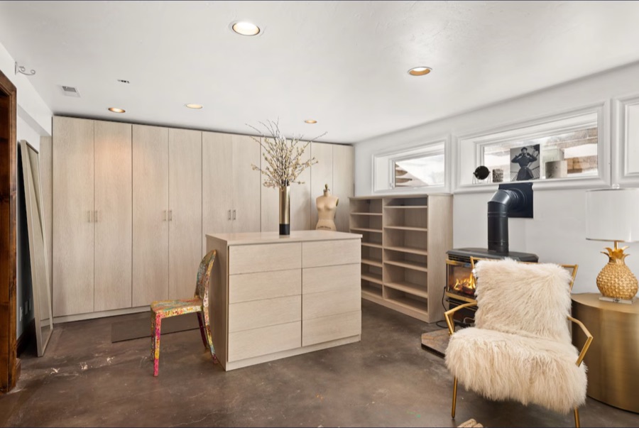 Den storage wall with pale wood wardrobes and an island dresser.